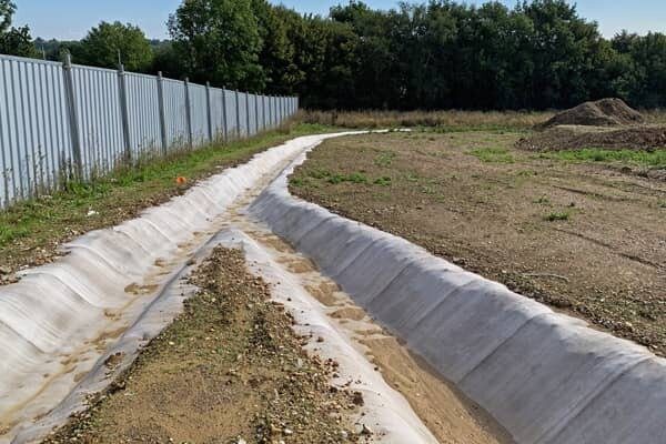 Photo of a Concrete Canvas lined channel on a HS2 Compound site. The channel splits into two separate channels at a fork.